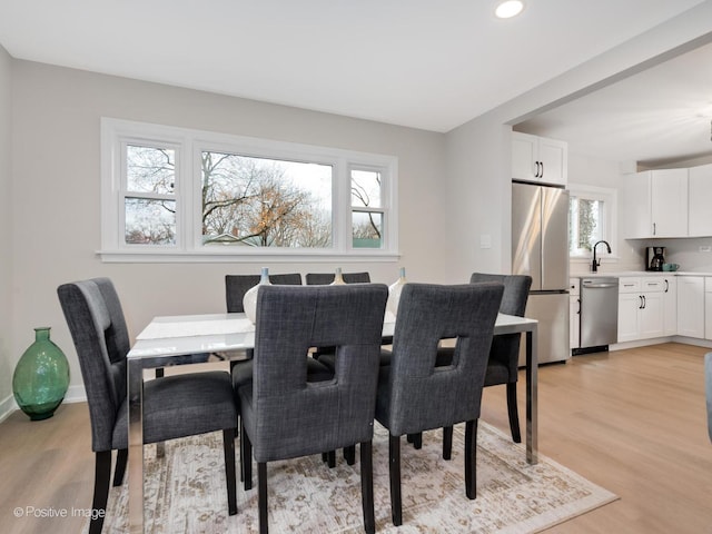 dining space with a wealth of natural light, sink, and light wood-type flooring