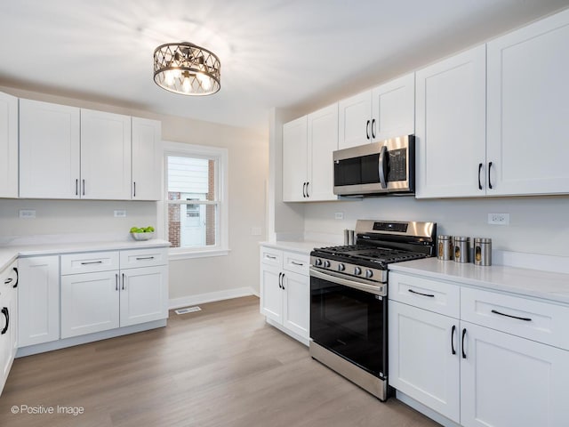 kitchen featuring appliances with stainless steel finishes, light hardwood / wood-style flooring, and white cabinetry