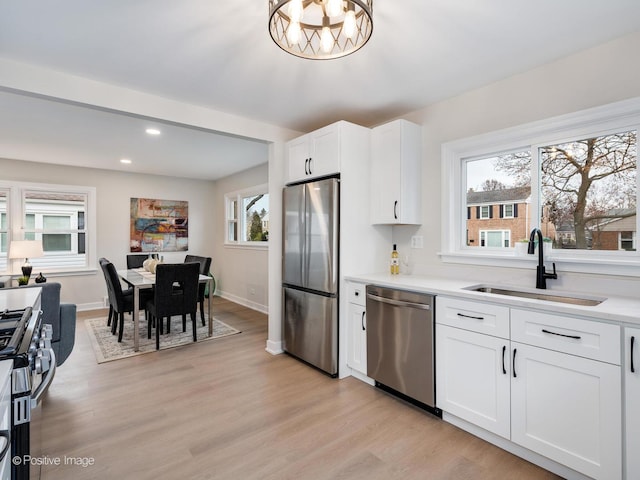 kitchen with a healthy amount of sunlight, white cabinetry, sink, and stainless steel appliances