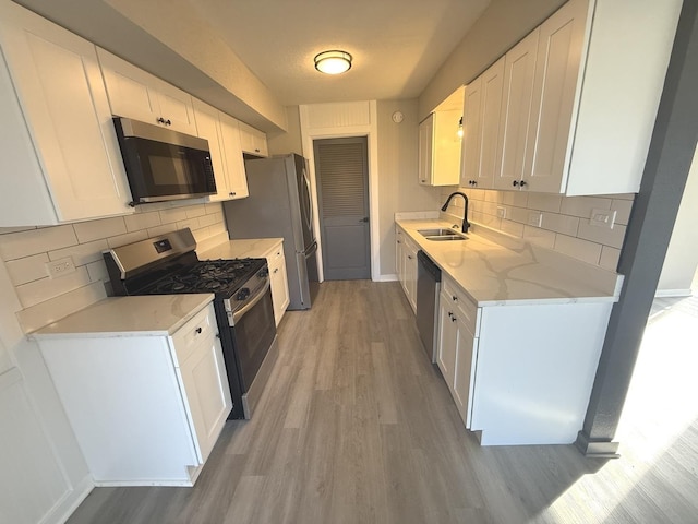 kitchen featuring appliances with stainless steel finishes, tasteful backsplash, white cabinetry, and sink