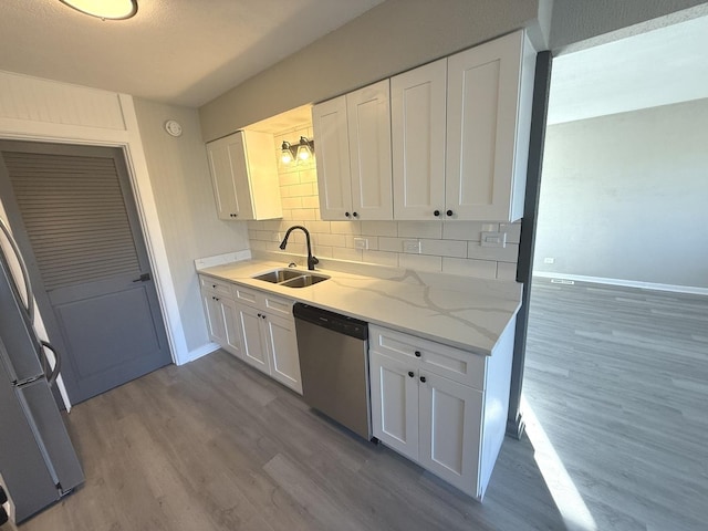 kitchen with white cabinetry, dishwasher, sink, backsplash, and hardwood / wood-style floors