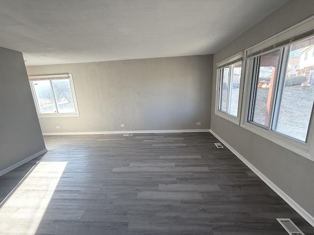 empty room with dark wood-type flooring and a healthy amount of sunlight