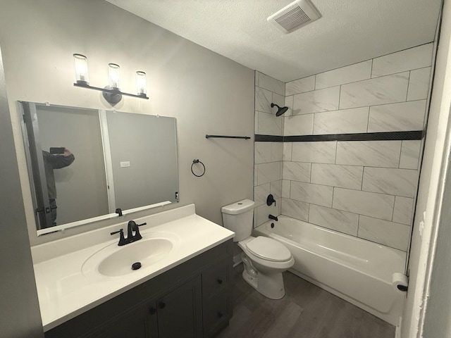 full bathroom featuring wood-type flooring, a textured ceiling, toilet, vanity, and tiled shower / bath