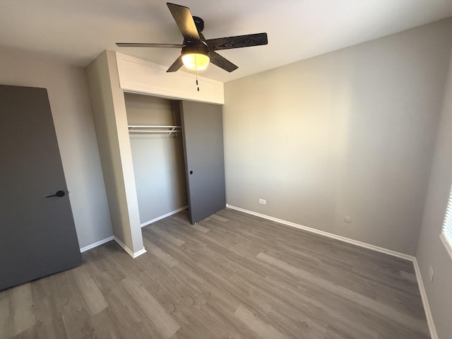 unfurnished bedroom with ceiling fan, a closet, and hardwood / wood-style flooring