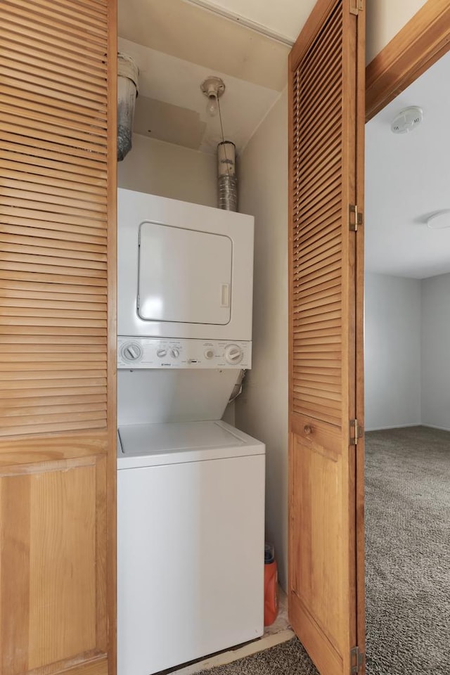 clothes washing area with carpet floors and stacked washer and dryer