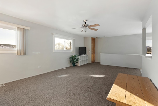 unfurnished living room with ceiling fan and dark colored carpet