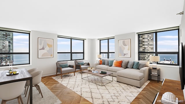 living room featuring a water view, a healthy amount of sunlight, and light parquet flooring