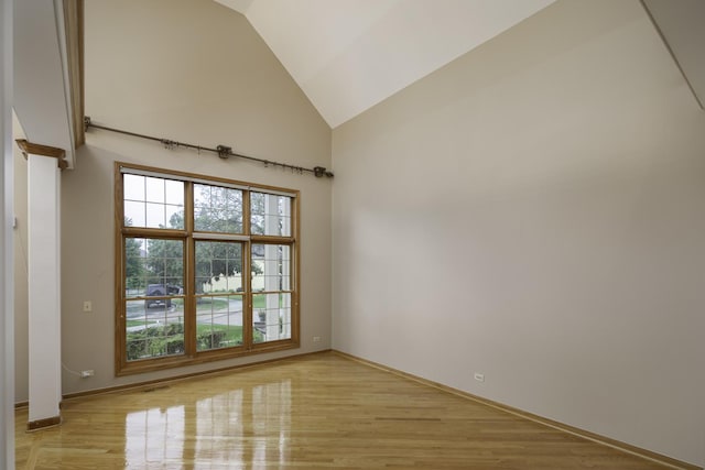 unfurnished room with light wood-type flooring and high vaulted ceiling