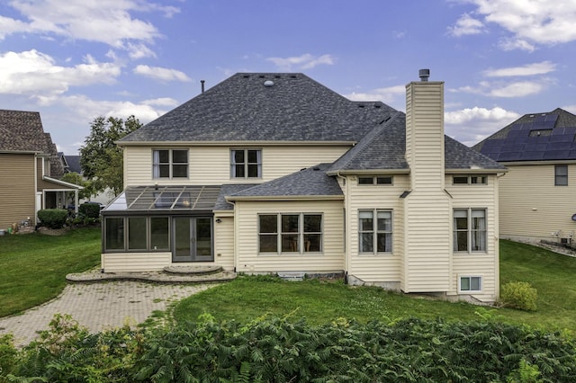 back of property with a yard, a patio, and a sunroom