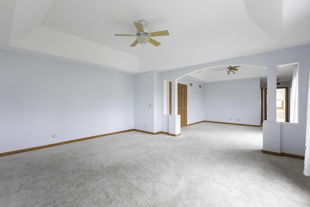 spare room with ceiling fan, light colored carpet, and a tray ceiling