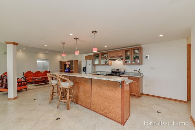 kitchen with white refrigerator with ice dispenser, stainless steel gas stove, decorative light fixtures, light stone counters, and a breakfast bar area