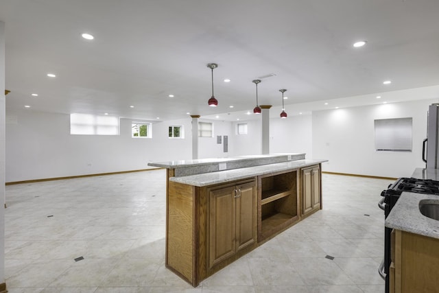 kitchen with light stone countertops, black stove, stainless steel fridge, decorative light fixtures, and a kitchen island