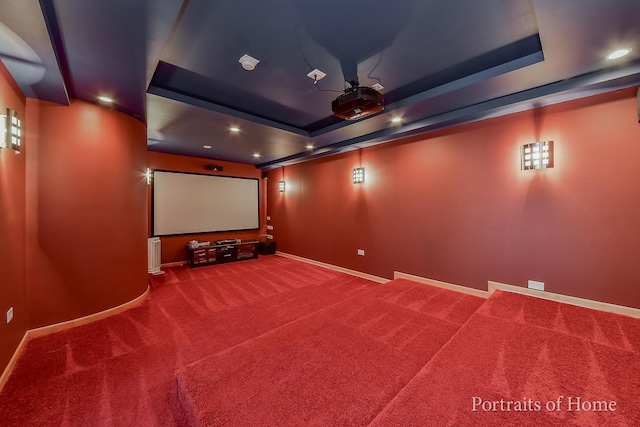 carpeted home theater room with a tray ceiling