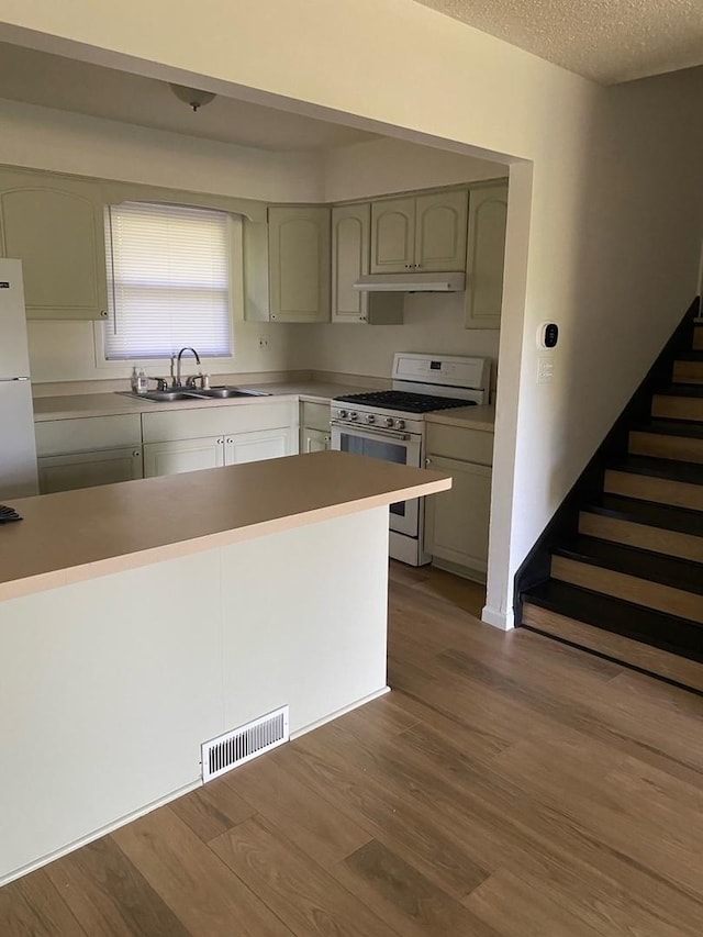 kitchen featuring white appliances, green cabinets, sink, a textured ceiling, and wood-type flooring