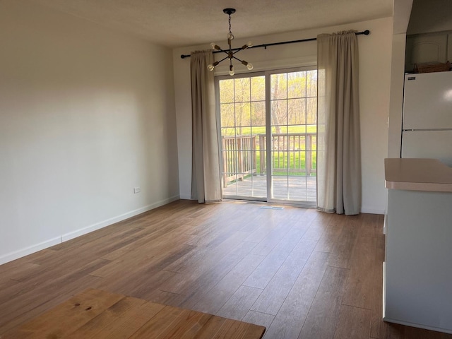 unfurnished dining area with a chandelier and wood-type flooring