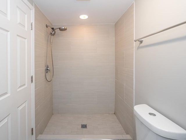 bathroom with tiled shower and toilet