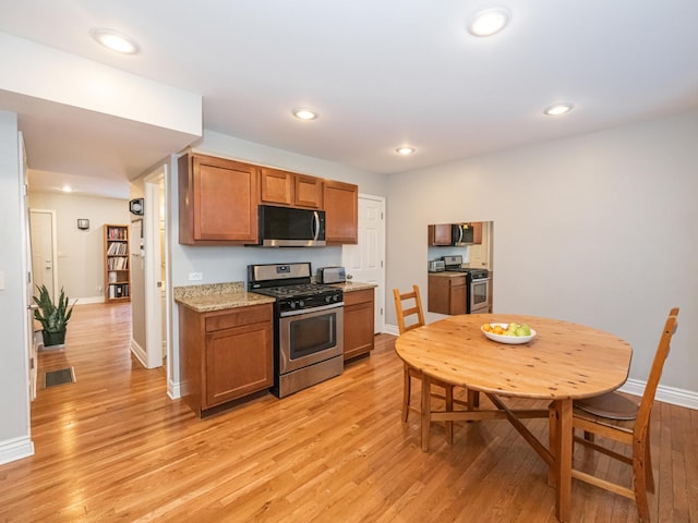 kitchen with light hardwood / wood-style flooring, light stone countertops, and appliances with stainless steel finishes