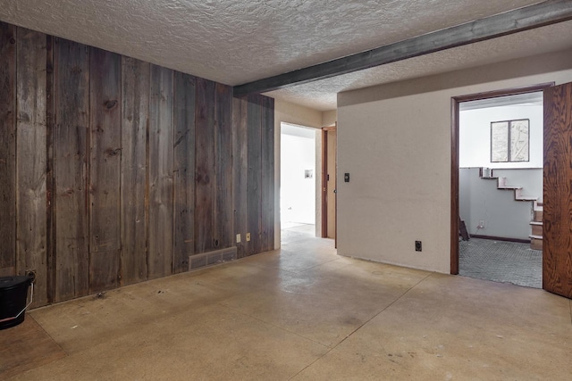 empty room with a textured ceiling and wood walls