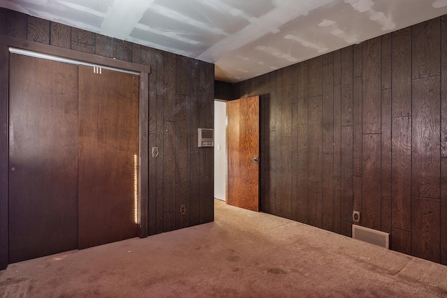 unfurnished bedroom featuring carpet and wooden walls