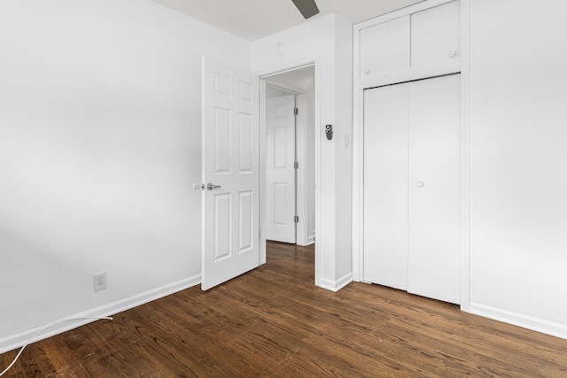 unfurnished bedroom with ceiling fan, dark wood-type flooring, and a closet