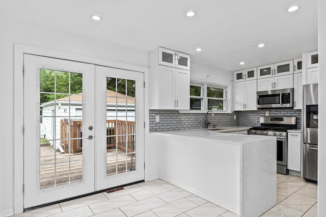 kitchen with kitchen peninsula, white cabinetry, sink, and stainless steel appliances