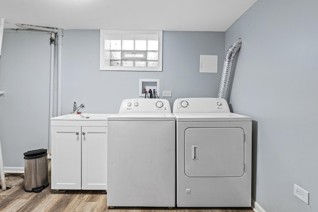 washroom featuring separate washer and dryer, sink, cabinets, and light hardwood / wood-style floors