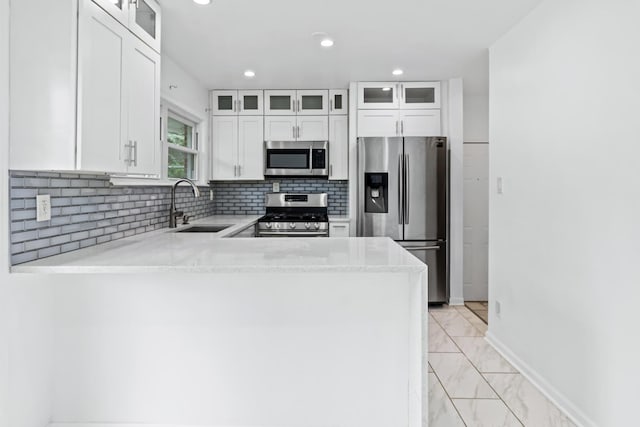 kitchen featuring white cabinetry, sink, stainless steel appliances, light stone counters, and kitchen peninsula