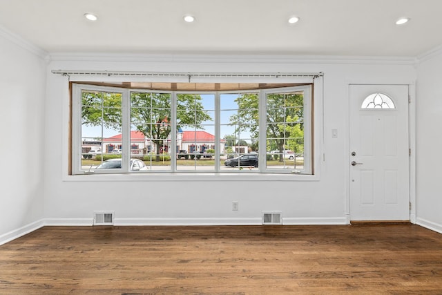 foyer entrance with dark wood-type flooring, crown molding, and a healthy amount of sunlight