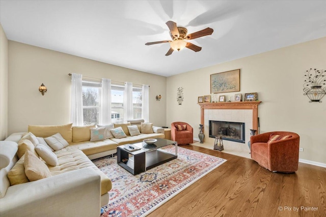 living room with ceiling fan, wood-type flooring, and a fireplace