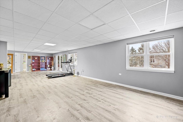 workout area with a paneled ceiling and light hardwood / wood-style floors