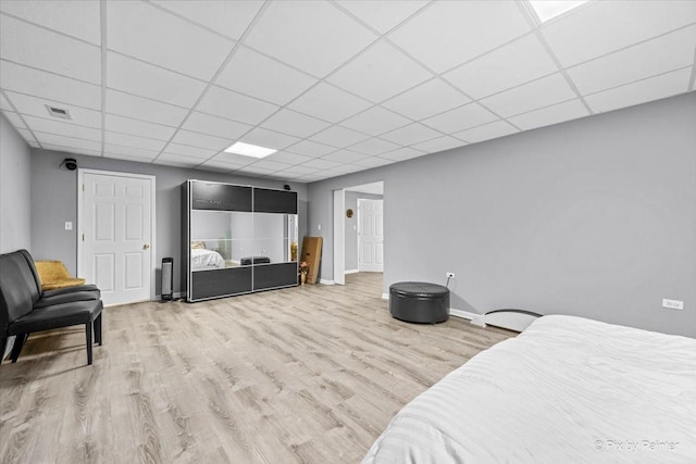 bedroom with a drop ceiling and light hardwood / wood-style floors