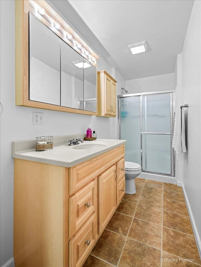 bathroom with vanity, toilet, and a shower with door