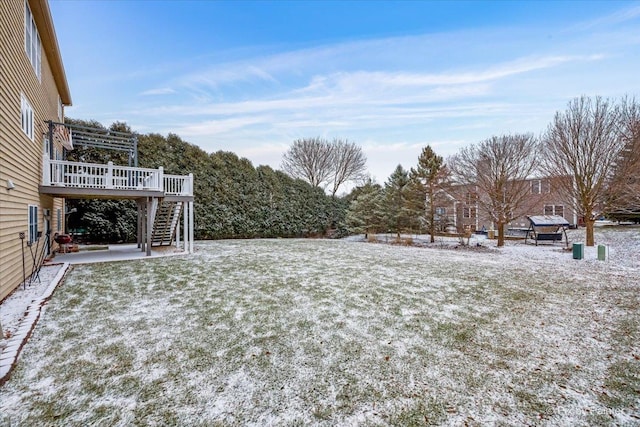 snowy yard featuring a patio area and a wooden deck