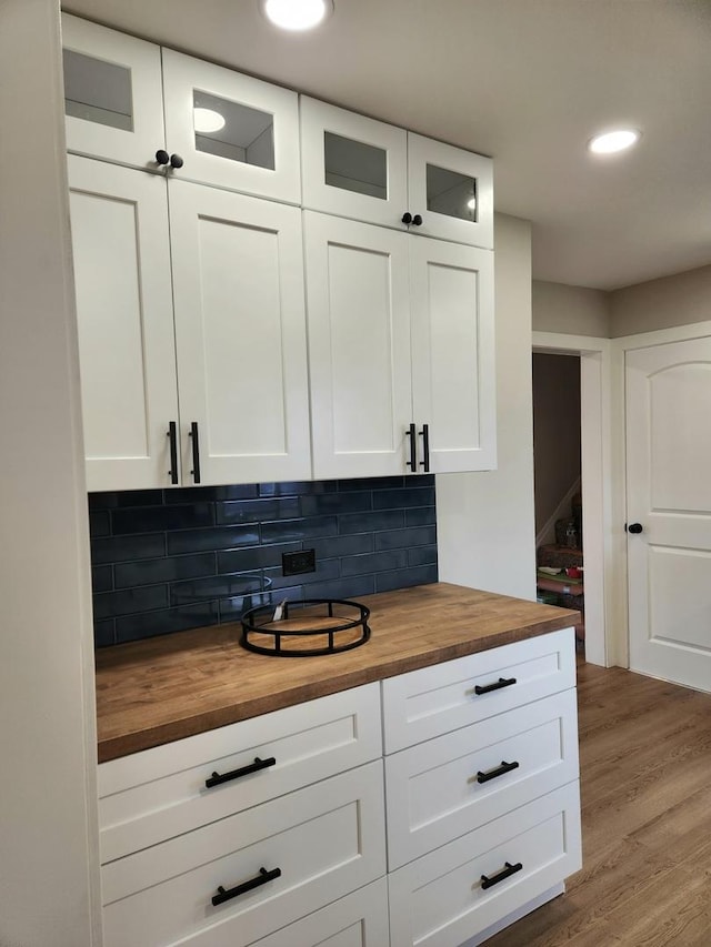 bar with decorative backsplash, white cabinets, wood counters, and light hardwood / wood-style flooring