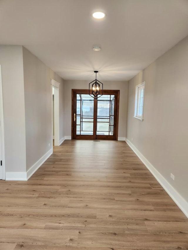 unfurnished dining area featuring an inviting chandelier and light wood-type flooring