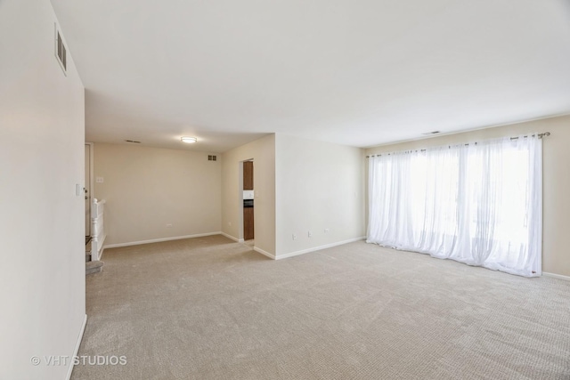 unfurnished room featuring visible vents, baseboards, and light colored carpet