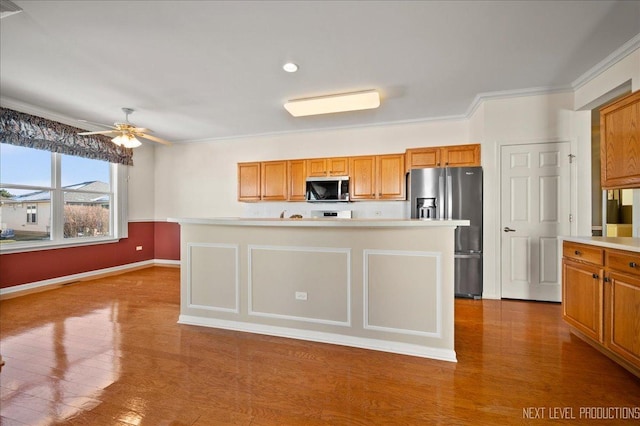 kitchen featuring appliances with stainless steel finishes, ceiling fan, crown molding, and hardwood / wood-style floors