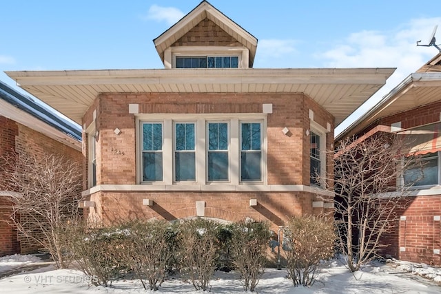 view of snowy exterior with brick siding