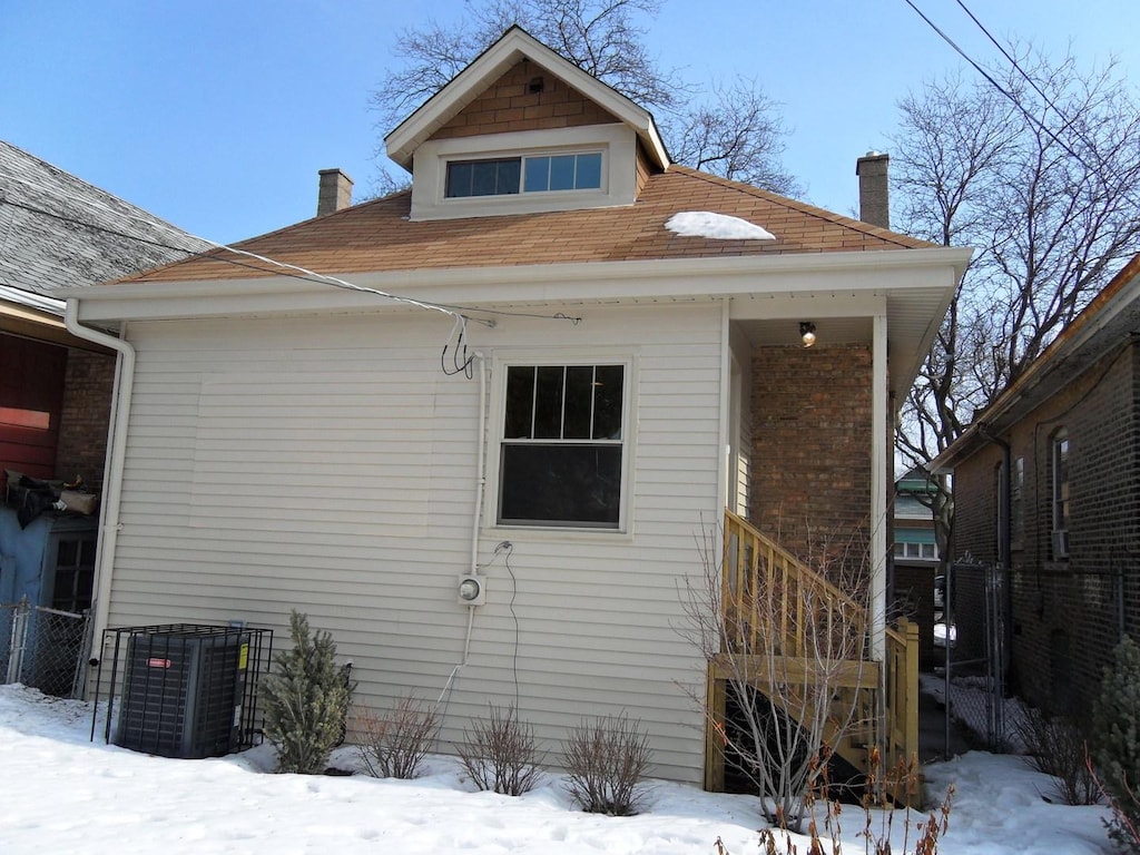 snow covered house featuring cooling unit