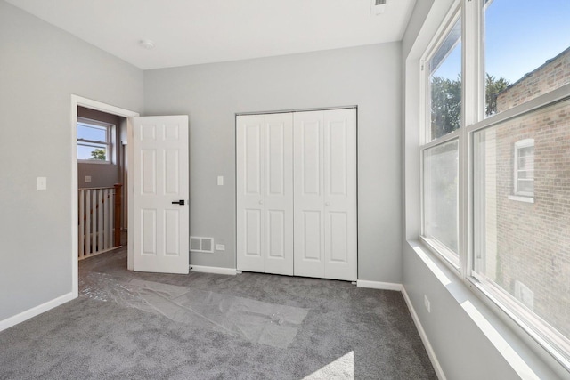 unfurnished bedroom featuring carpet flooring, multiple windows, and a closet