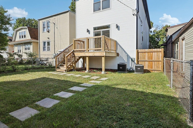 rear view of house featuring a wooden deck, a yard, and central AC