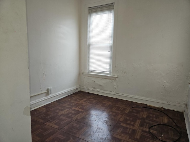 spare room featuring dark parquet flooring and a healthy amount of sunlight