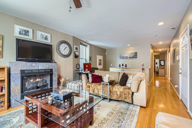 living room featuring light wood-type flooring and a tiled fireplace