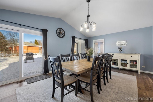 dining space featuring a healthy amount of sunlight, vaulted ceiling, a chandelier, and hardwood / wood-style flooring