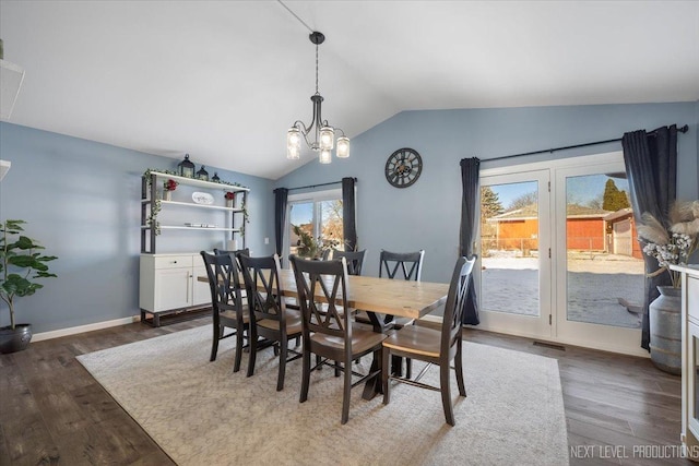 dining room with a notable chandelier, dark hardwood / wood-style flooring, and vaulted ceiling