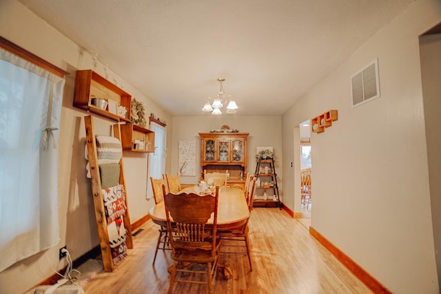 dining area with an inviting chandelier and light hardwood / wood-style flooring