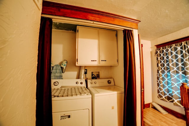 laundry area with cabinets, a textured ceiling, light hardwood / wood-style flooring, and washing machine and clothes dryer