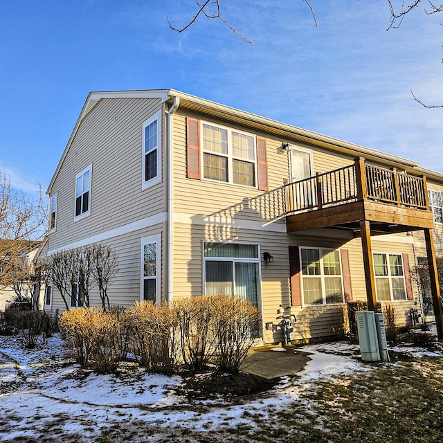 snow covered back of property with a wooden deck