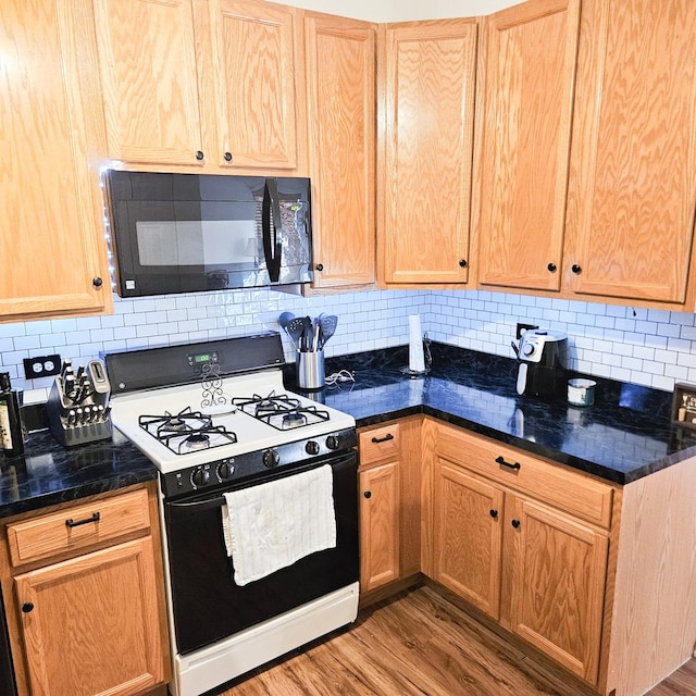 kitchen with decorative backsplash, wood-type flooring, and white gas range oven