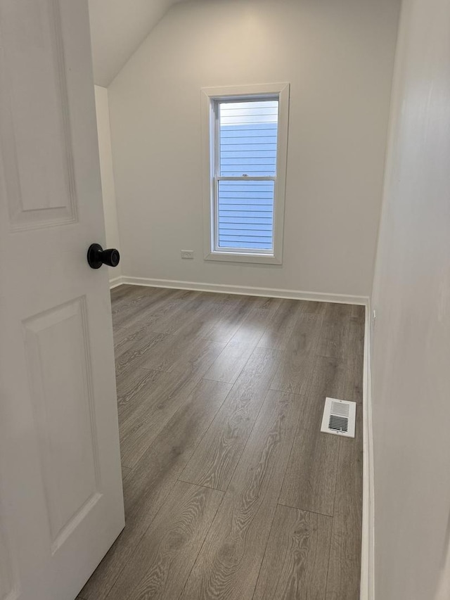 unfurnished room with light wood-type flooring and vaulted ceiling